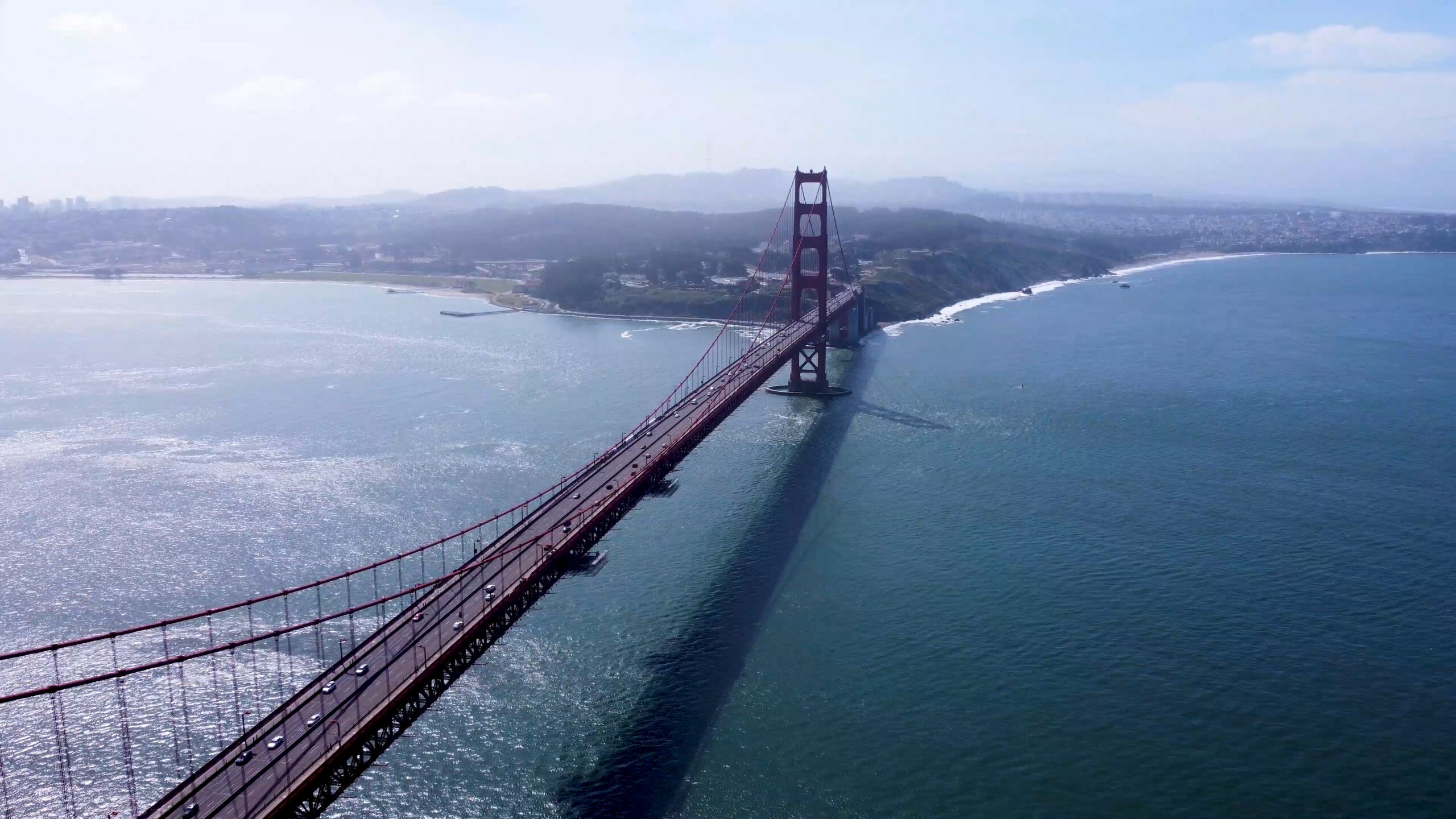 An arial image of the golden gate bridge on a slightly hazy day under a blue sky