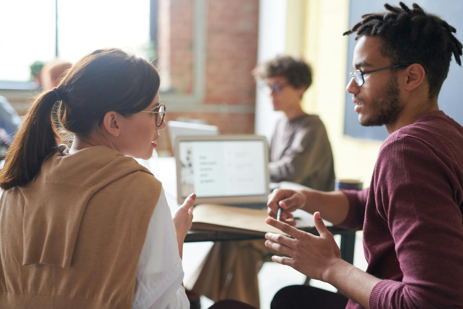 woman and man talking in front of a laptop in an office space